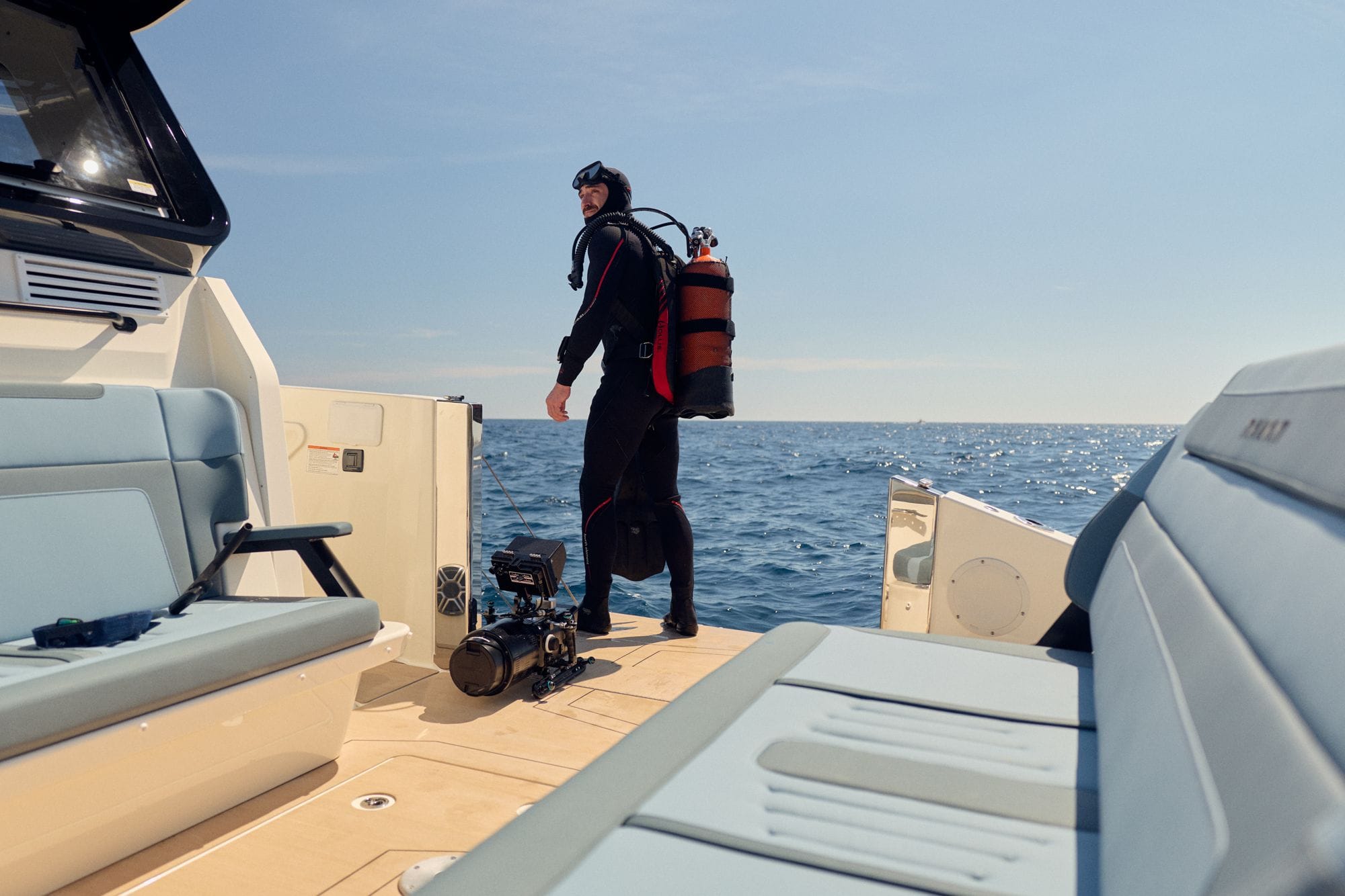 A diver in a wetsuit and tank standing in the C38 cockpit